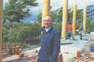 Bild von Torsten Koop vor Gedenkdalben (in den Hafengrund gerammte Pfahle). Im Hintergrund sind Bauarbeitende. Der Boden wird neu gepflastert.