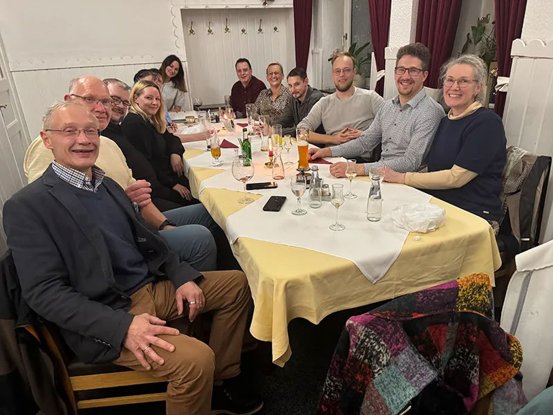 Foto von der Belegschaft des Bestattungsinstitut Koop an einem fein gedeckten Tisch in einem Restaurant. Alle lächeln in die Kamera.